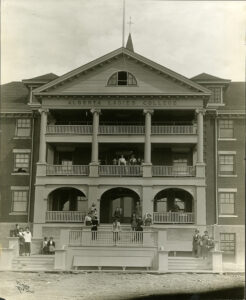 Exterior of the Alberta Ladies College, Red Deer. Woman stand outdoors on verandas.